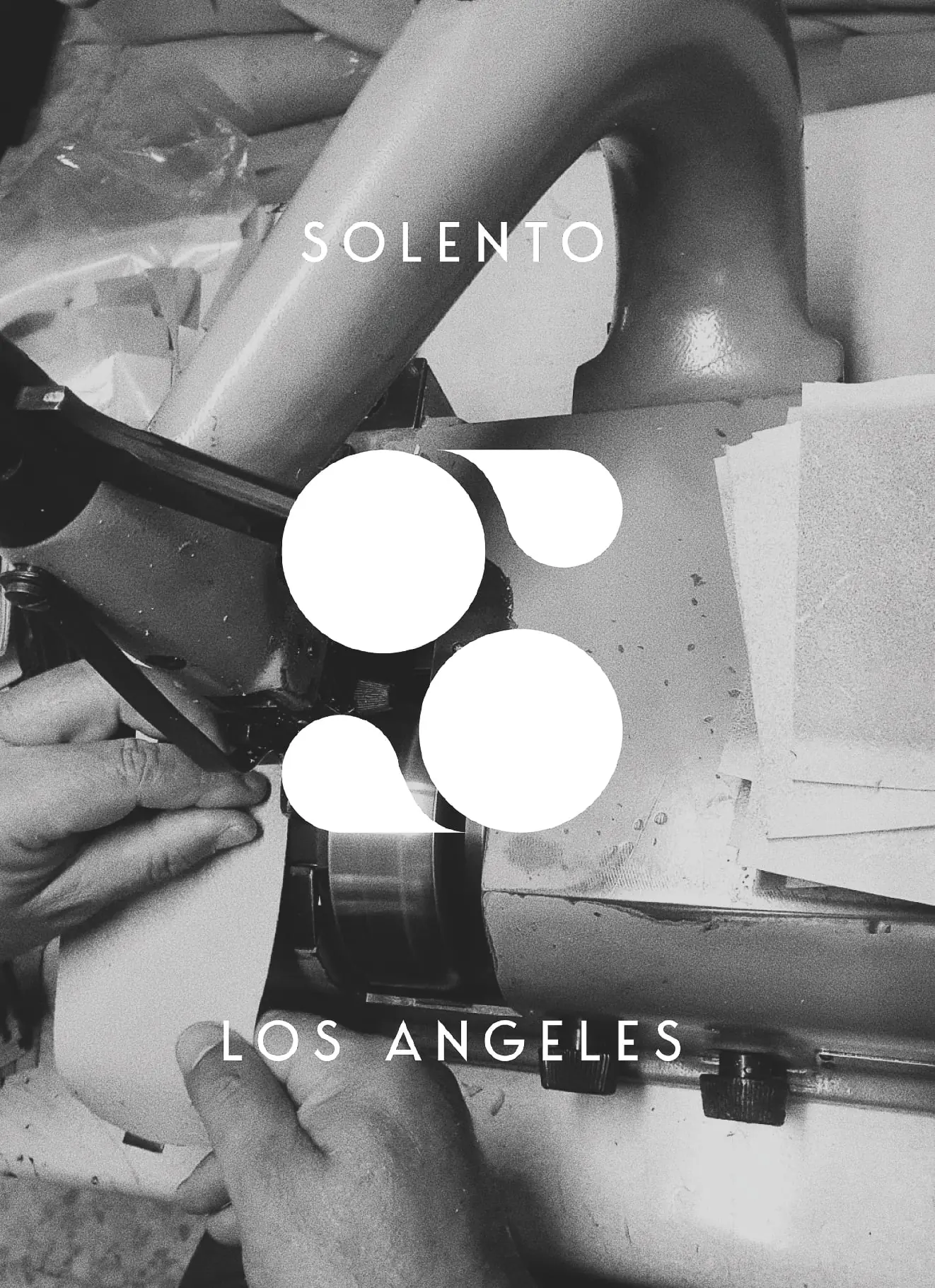 White logo and Los Angeles wordmark over a black-and-white photo of hands feeding leather into a skiving machine, for Solento.